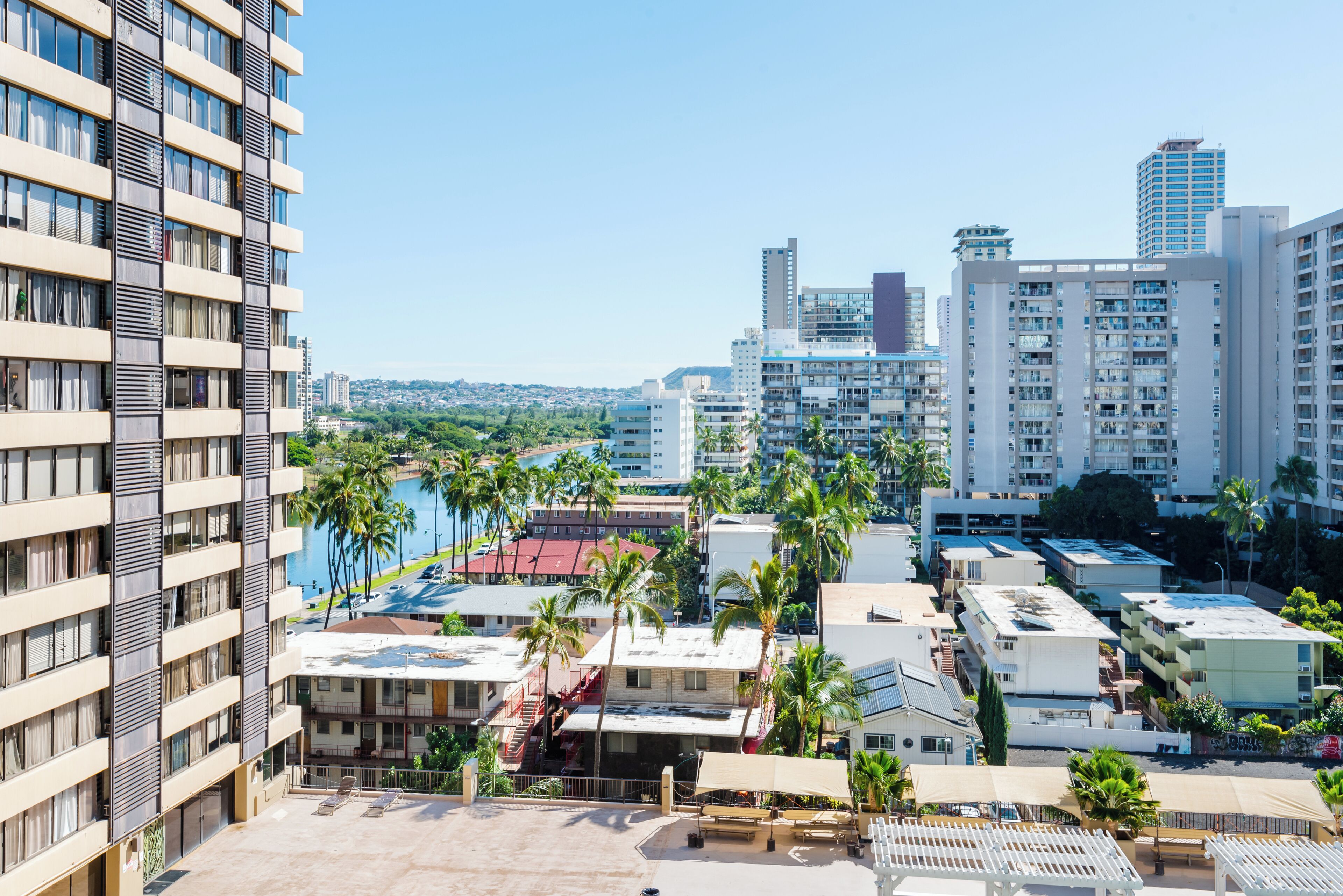A high-rise hotel with multiple floors, balconies, and a view of a marina with palm trees.