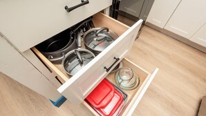 A kitchen drawer with pots, pans, and a measuring cup. - Royal Aloha by Tropical Escapes Realty (Honolulu)