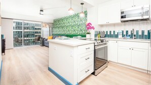 A modern kitchen with white cabinetry, a central island with drawers, a built-in oven, and a microwave above the counter. - Royal Aloha by Tropical Escapes Realty (Honolulu)