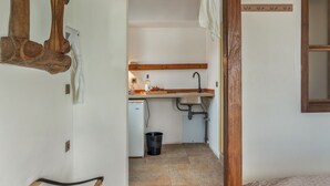 Un corridoio stretto che conduce a una cucina con lavandino, piccolo frigorifero e soffitto con travi in legno.