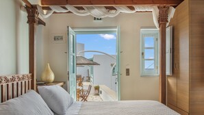 Una camera da letto con un letto, un armadio in legno e un balcone con tavolo e sedie.