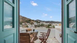 Un balcone con tavolo e sedie, vista su un villaggio costiero.