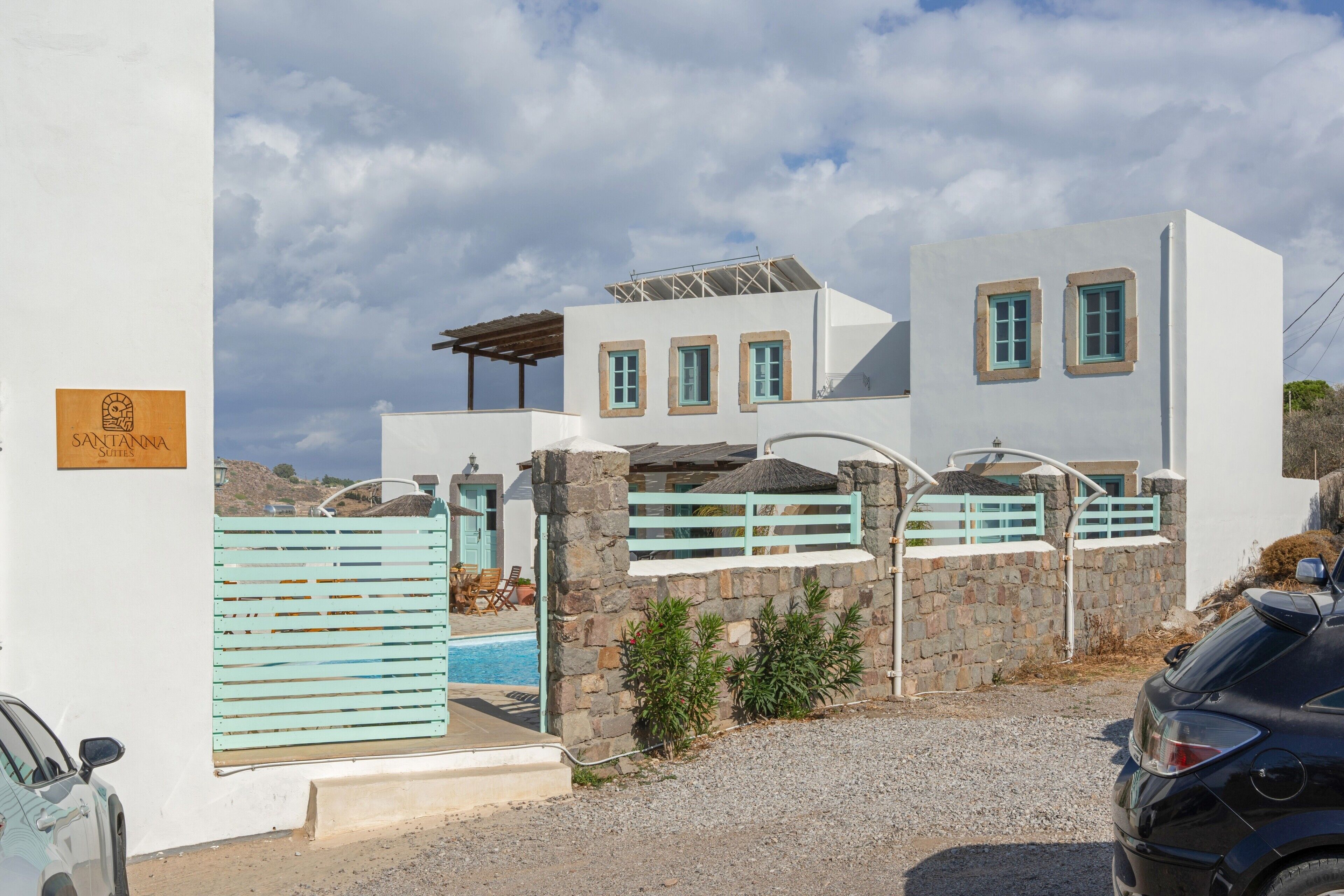 Un bâtiment moderne doté d’une piscine, de murs en pierre et d’une enseigne sur laquelle on peut lire « SANTANNNA ».