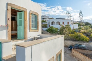 Un bâtiment blanc avec une porte verte, un petit balcon et une voiture garée.