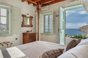 Une chambre à coucher avec un lit, une commode, un miroir et une vue sur la mer.