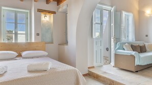 A bedroom with a bed, a sofa, a wooden ceiling, and a large window. - Room 'Triple  Pool View No 2' with Shared Pool, Wi-Fi and Air Conditioning (Patmos)
