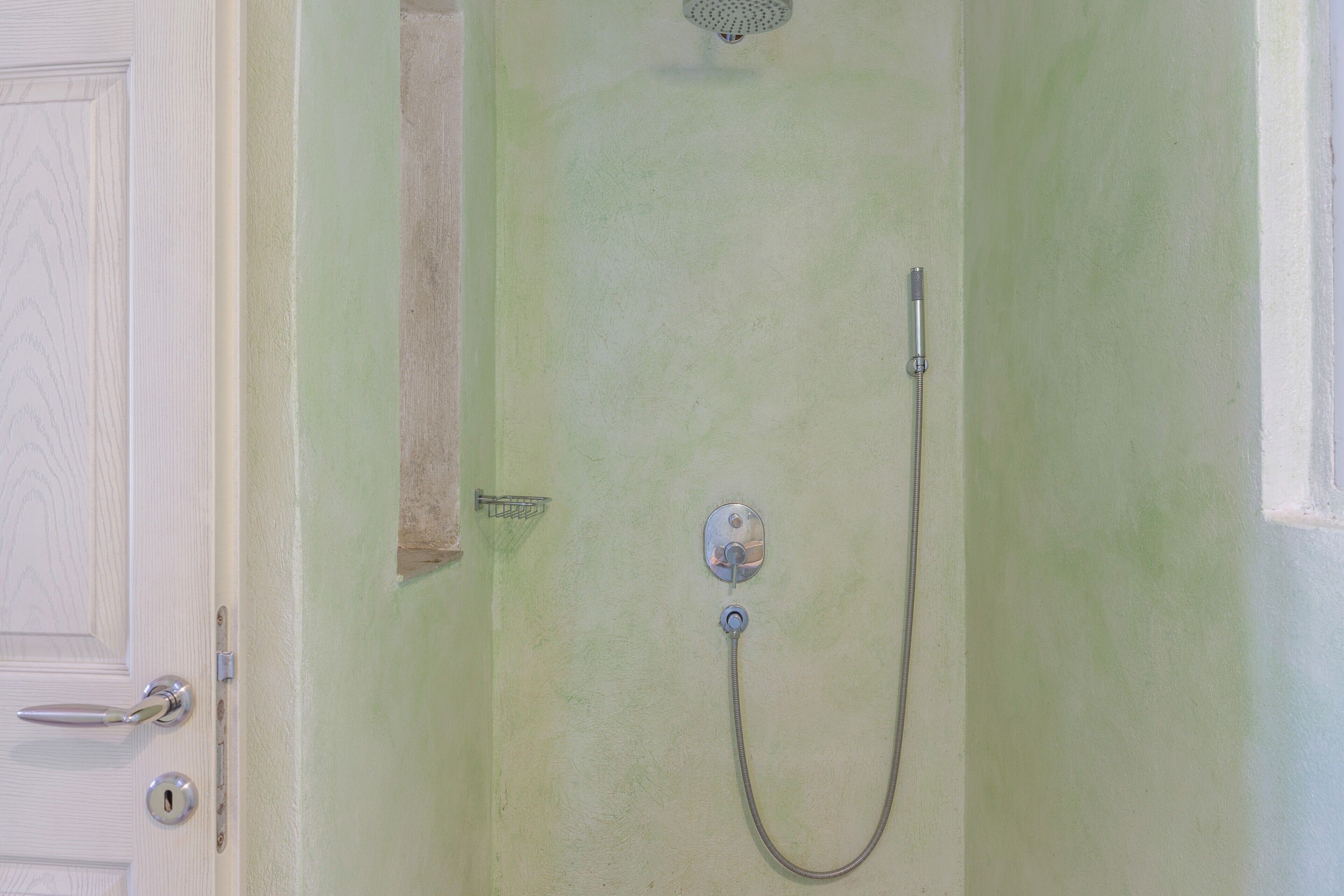 A bathroom with a shower, a towel rack, and a door with a handle.