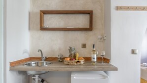 A kitchen with a sink, a wooden countertop, a fruit basket, a bottle, and a wine glass. - Room 'Triple  Pool View No 2' with Shared Pool, Wi-Fi and Air Conditioning (Patmos)