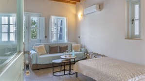 A room with a bed, a sofa, a small table, and a window with curtains. - Room 'Triple  Pool View No 2' with Shared Pool, Wi-Fi and Air Conditioning (Patmos)