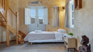 Une chambre à coucher avec un lit, un escalier en bois, une fenêtre avec des rideaux et une petite table de chevet sur laquelle est posée une plante.