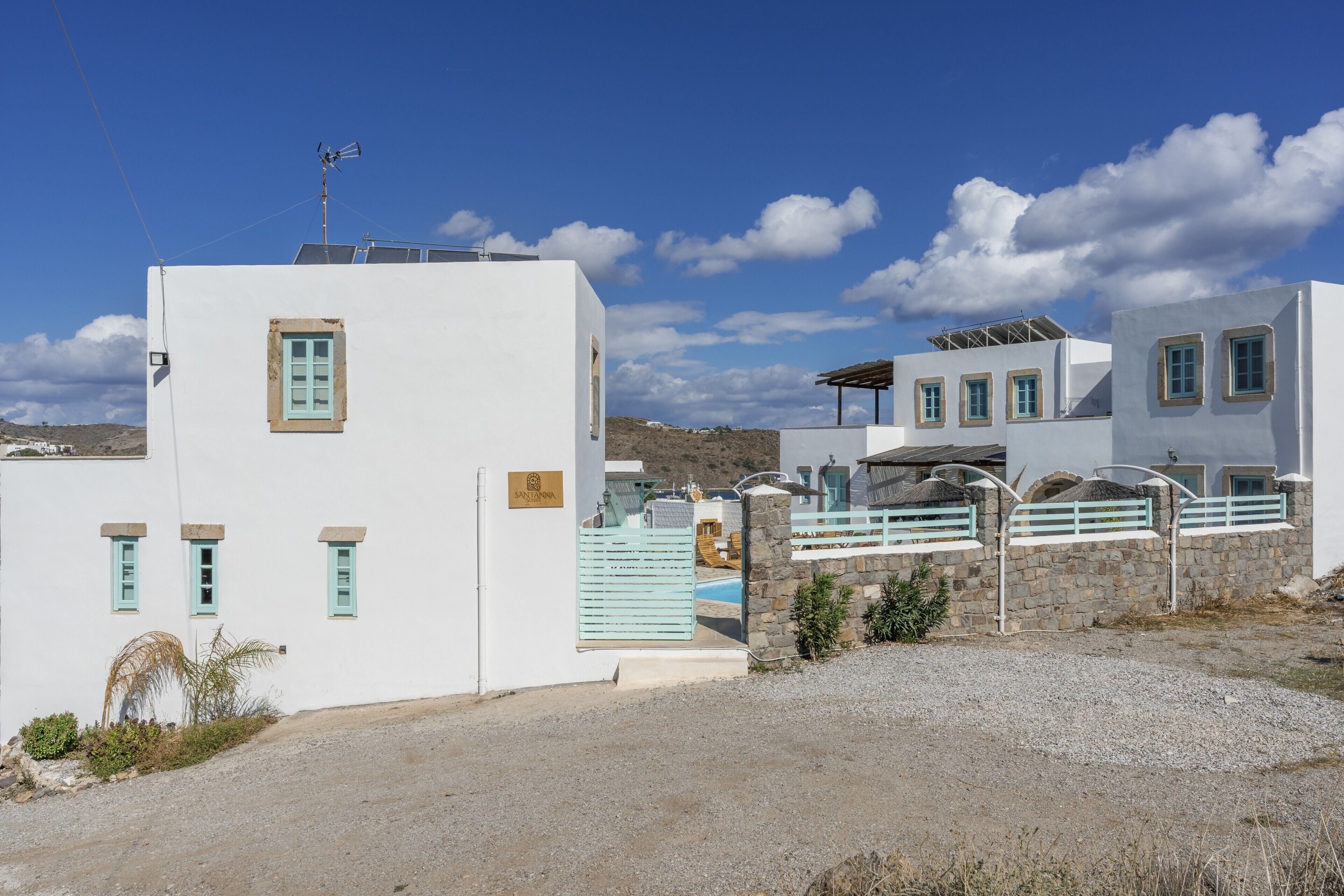 Un bâtiment blanc avec une piscine, des murs en pierre et un ciel dégagé.