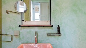 A bathroom with a sink, mirror, towel rack, and toiletries.