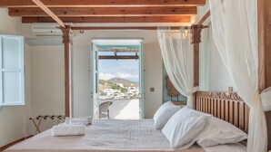 Ein Schlafzimmer mit Bett, Blick auf eine Stadt und einem Balkon.