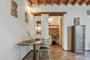 Ein Essbereich mit Tisch, Stühlen, einem Schrank und einer Küche im Hintergrund.