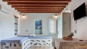 A room with a stone wall bed, a wooden ceiling, a television, and a table with fruit.