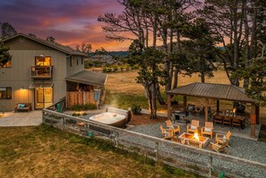 Una casa de dues plantes amb un pati que inclou una banyera hidromassatge, seients exteriors i una zona de barbacoa coberta.