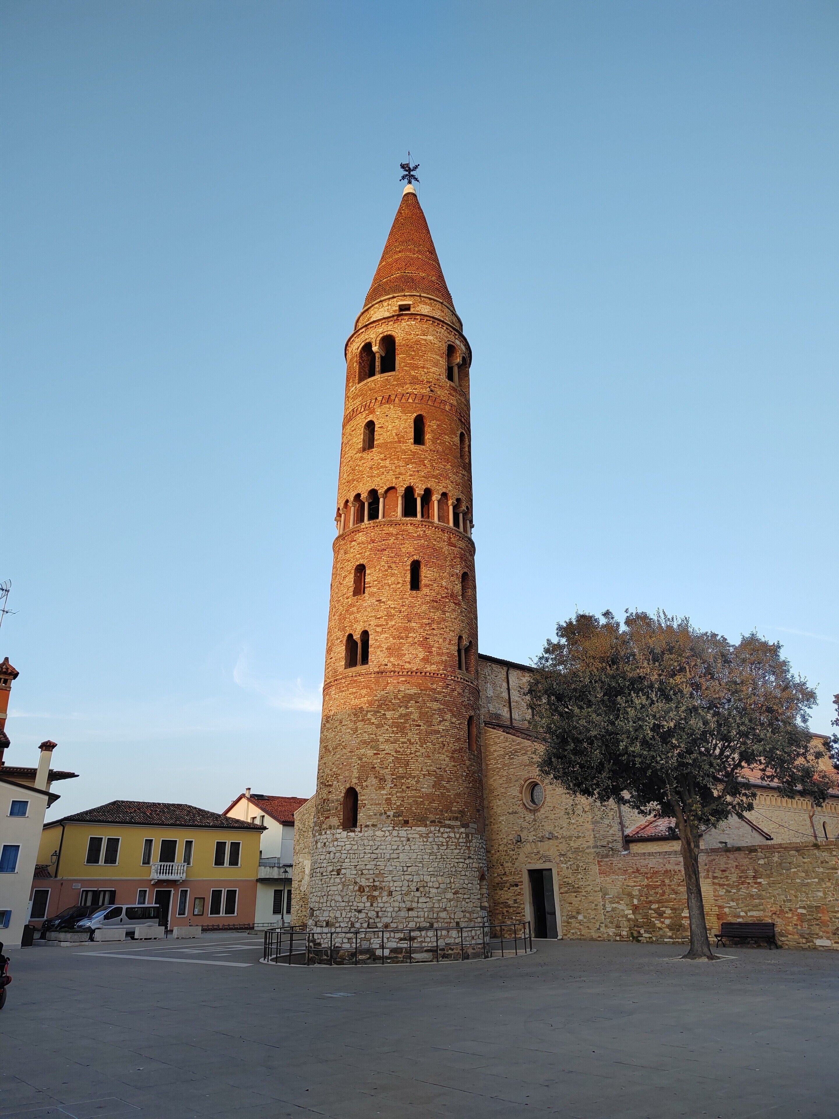 Ein historischer Turm mit einem spitz zulaufenden Dach, einem steinernen Fundament und einem Winddreher.
