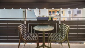 A balcony with two chairs and a small table, a view of buildings, and a covered area with a railing. - Apartment 'Appartamento Bettin' with Private Terrace, Wi-Fi and Air Conditioning (Caorle)