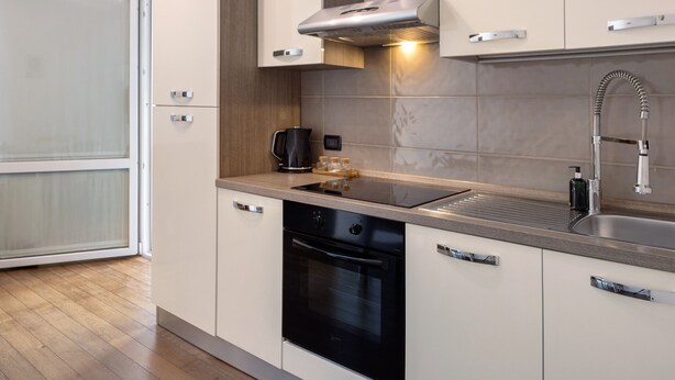 A modern kitchen with a built-in oven, a stainless steel sink, and a range hood. - Apartment 'Appartamento Bettin' with Private Terrace, Wi-Fi and Air Conditioning (Caorle)