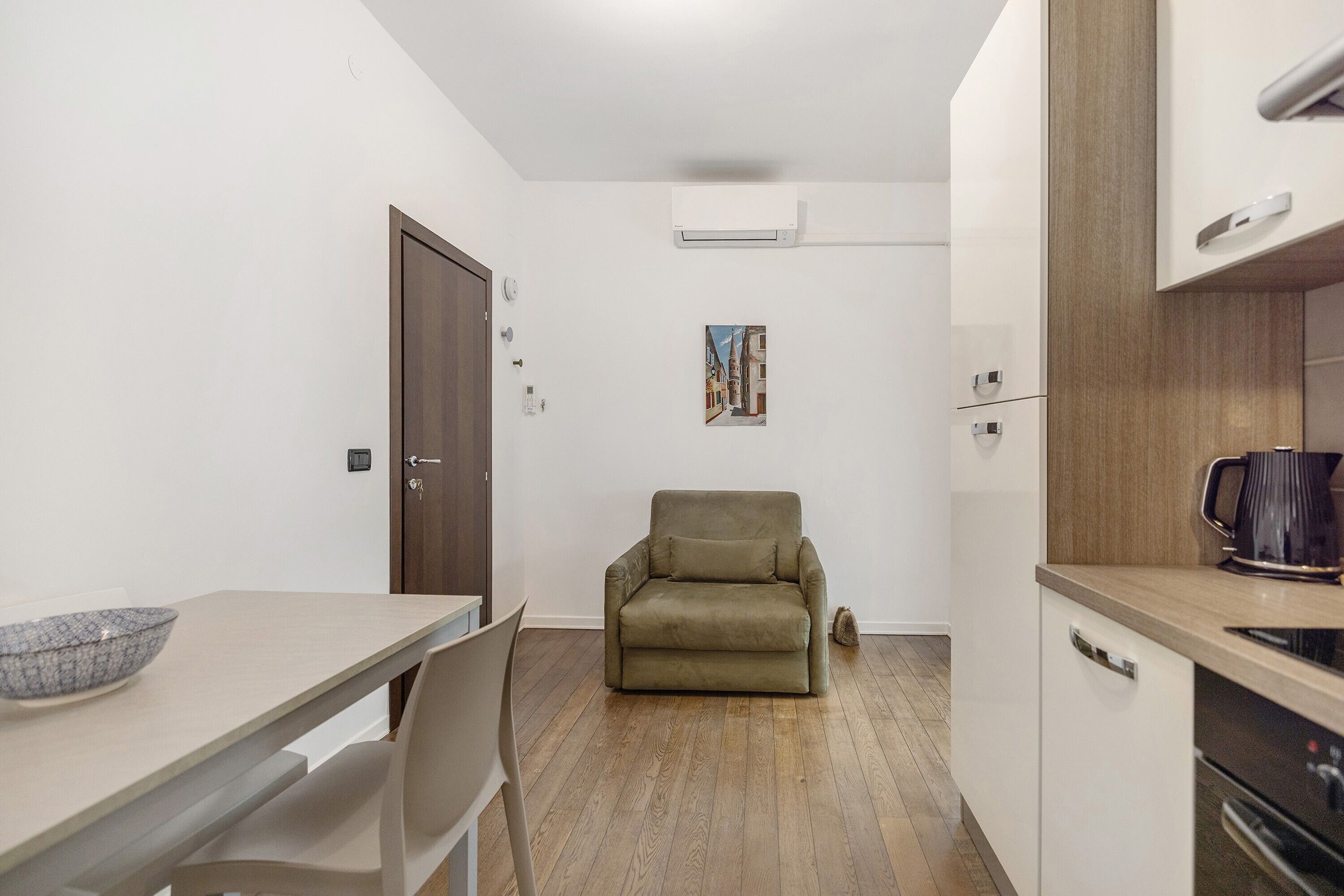 Una cocina compacta con comedor, un sofá y una cafetera.