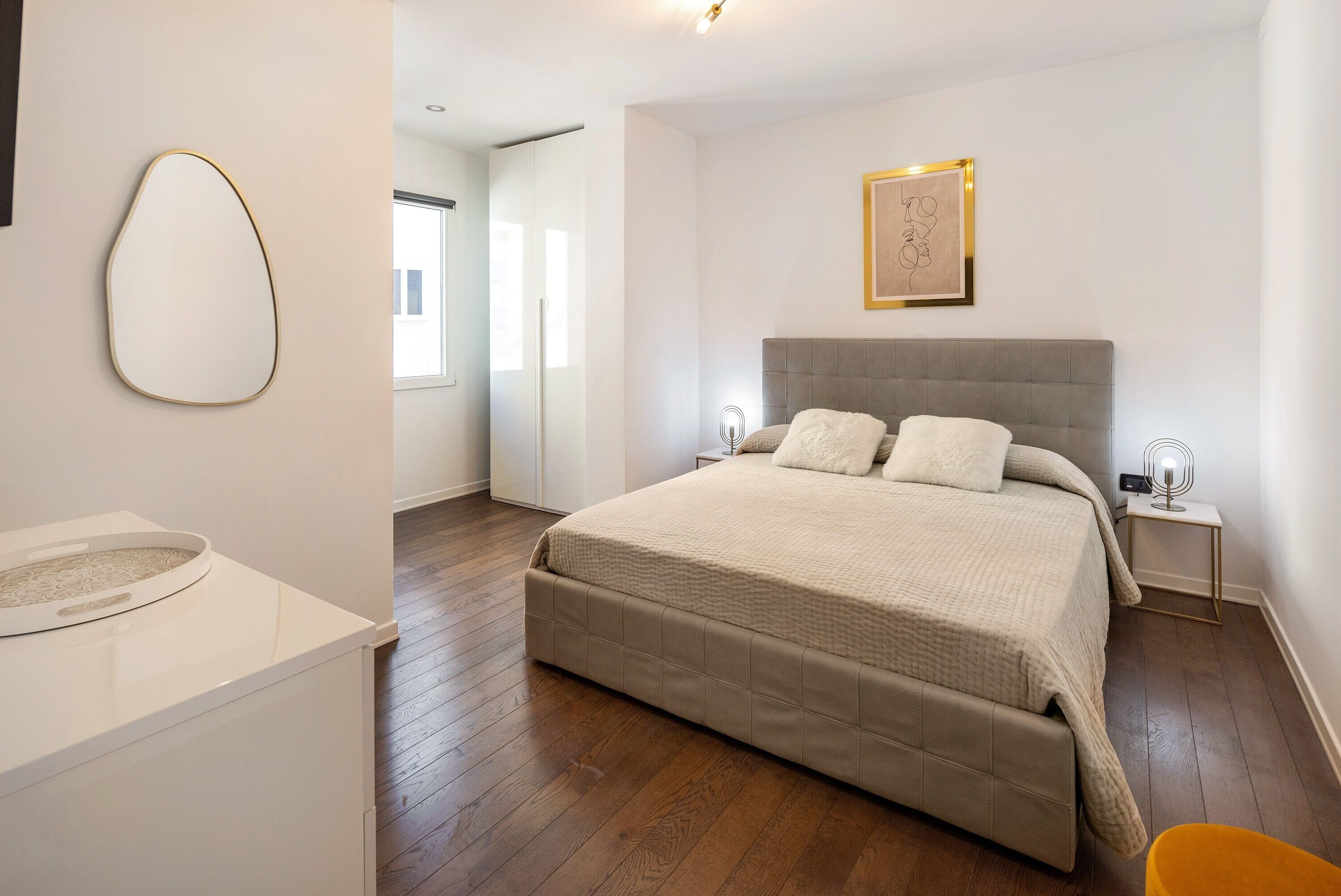 Un dormitorio con una cama grande, mesitas de noche, una obra de arte en la pared y una ventana.
