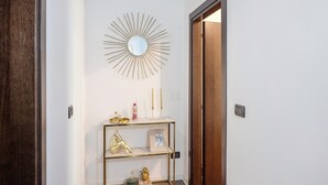 A hallway with a gold-framed console table, a mirror, and a wooden door. - Apartment 'Appartamento Bettin' with Private Terrace, Wi-Fi and Air Conditioning (Caorle)