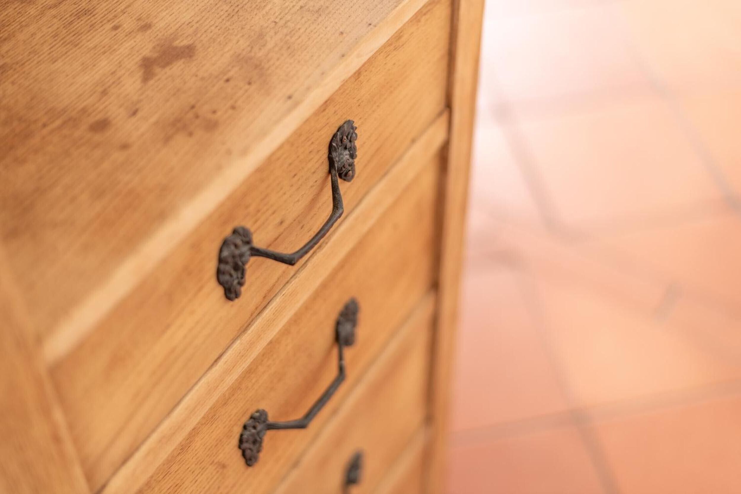 Een houten dressoir met versierde metalen handgrepen.