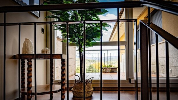 A staircase with a metal railing, a wooden chair, a potted plant, and a wicker basket. - Villa 'Casa El Rasillo' with Lake View, Private Terrace and Wi-Fi (El Rasillo de Cameros)