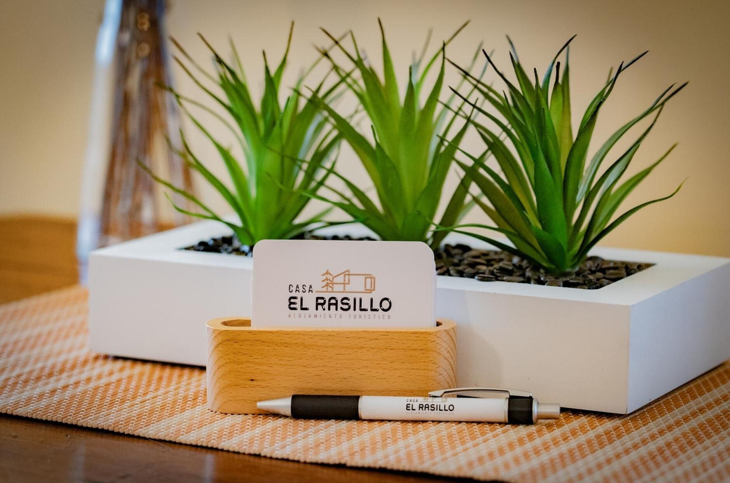 Una caja de madera con un cartel que dice 'CASA EL RASILLO' y un bolígrafo a su lado.