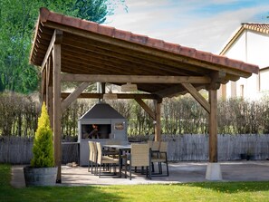 Puurakenteinen pergola, jossa on sisäänrakennettu grilli ja oleskelualue.