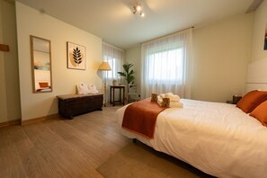 Hotellihuone, jossa on suuri sänky, lipasto, peili ja ikkuna, jossa on verhot.
