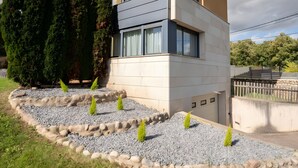 A modern two-story house with a flat roof, large windows, and a stone pathway leading to the entrance. - Villa 'Casa El Rasillo' with Lake View, Private Terrace and Wi-Fi (El Rasillo de Cameros)