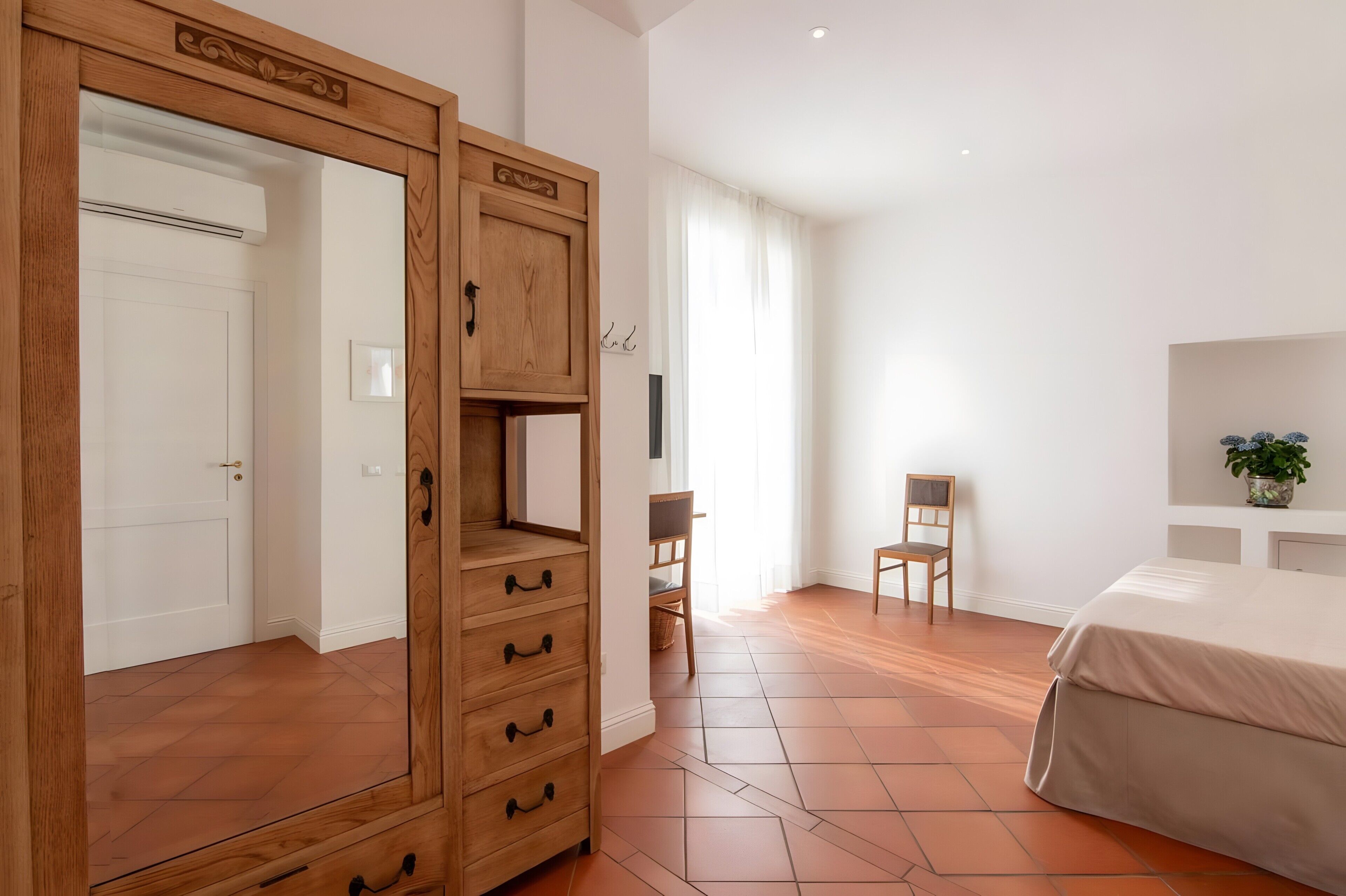 A bedroom with a wooden wardrobe, a bed, a desk, and a chair.