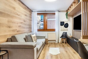Un salon moderne avec un canapé, un téléviseur, un radiateur et une fenêtre avec des rideaux.