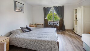 Une chambre à coucher comprenant un lit, un bureau, une chaise, une armoire et une fenêtre avec des rideaux.