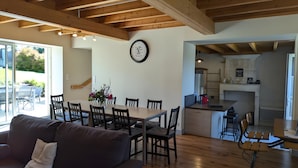 A modern interior with a dining area, kitchen, and a sofa with a view to the outside. - Holiday Home 'La Bonne Chauffe' with Shared Pool, Private Terrace and Wi-Fi (Verrières)