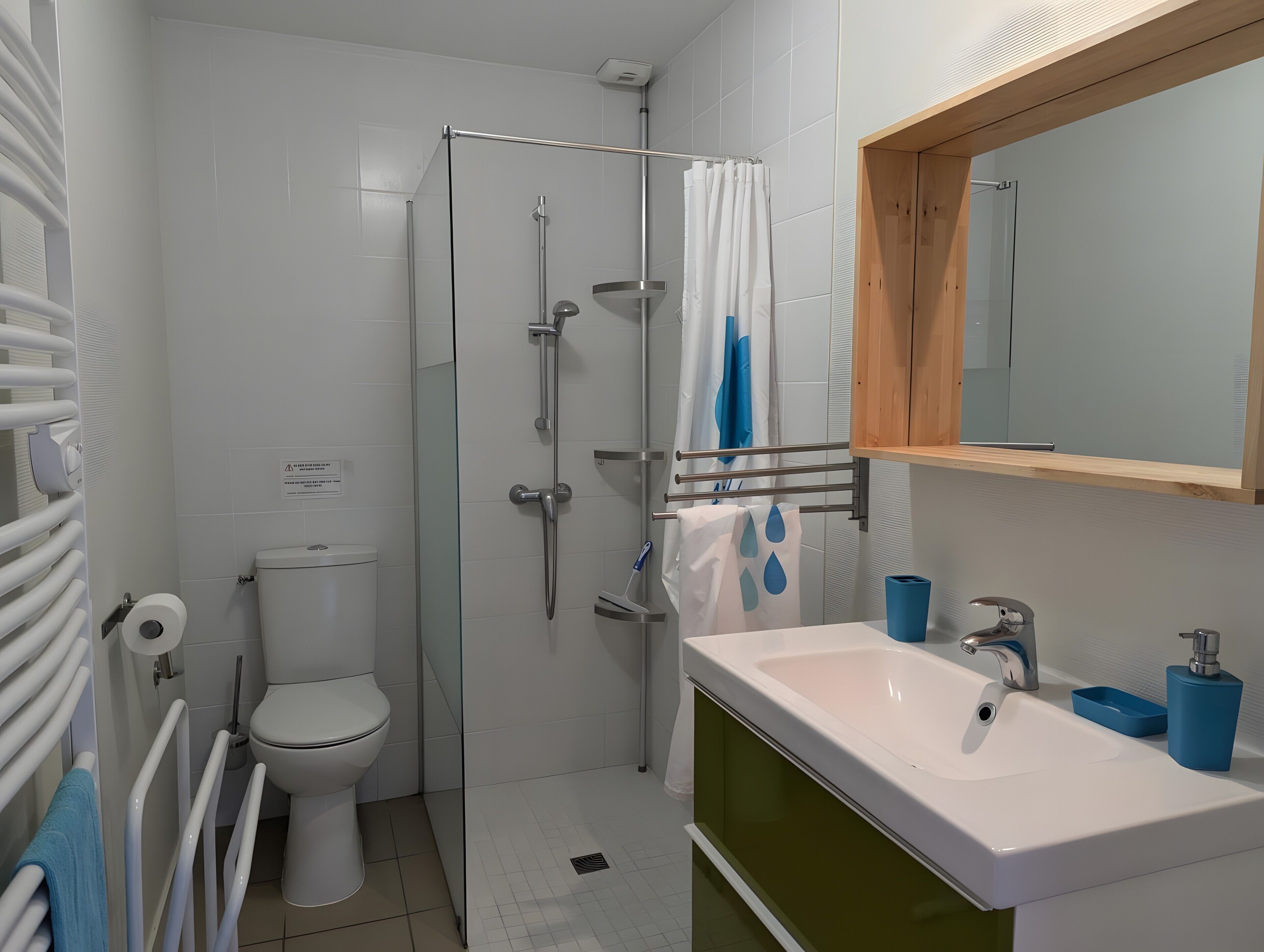 A bathroom with a toilet, shower, sink, and mirror.