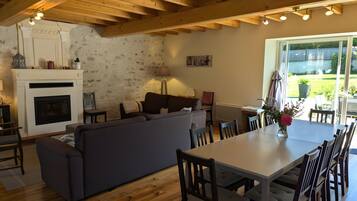 Un salon chaleureux avec une cheminée, un canapé, une table à manger et des chaises.