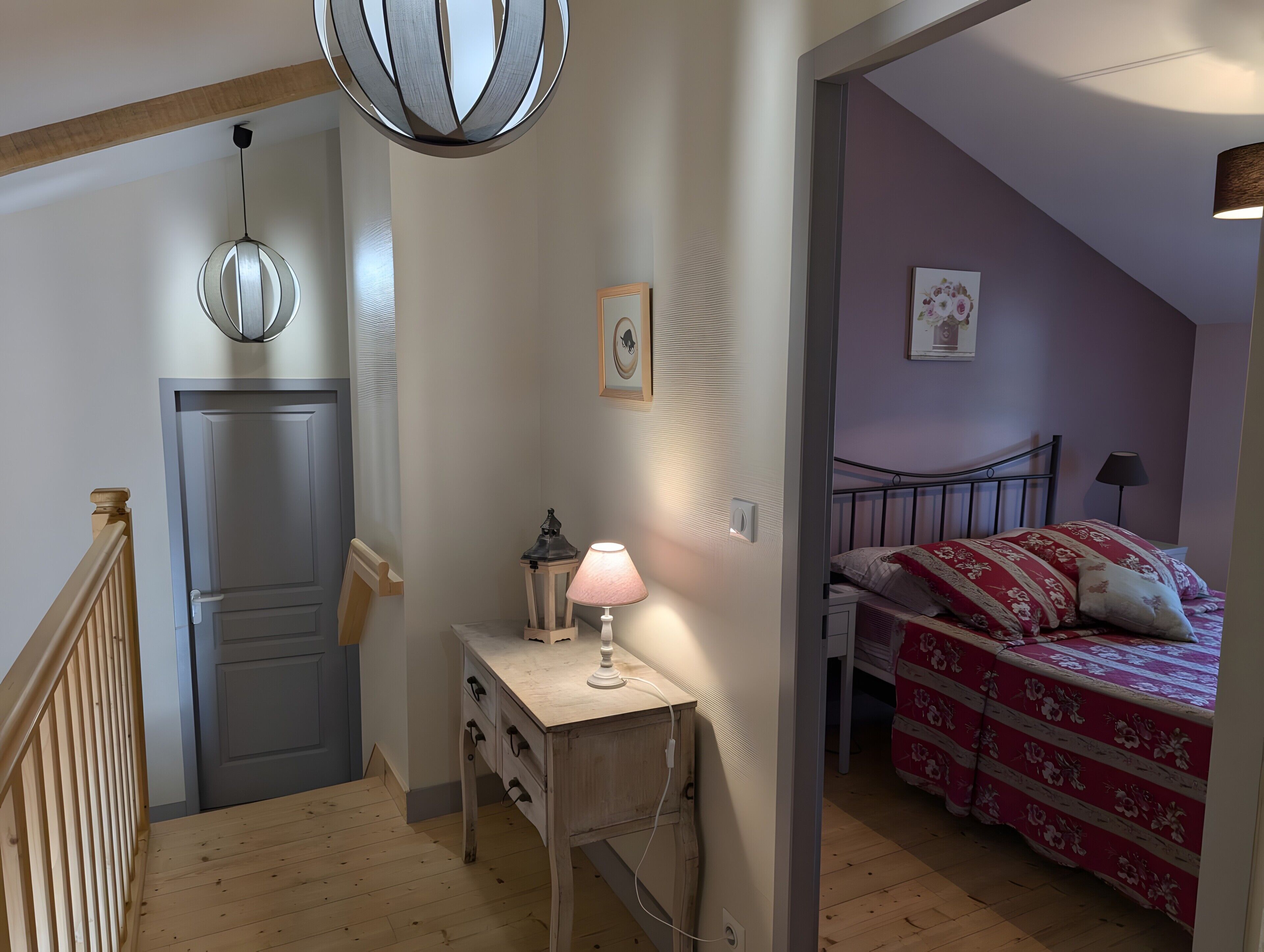 Une chambre à coucher avec un lit, une table de chevet avec une lampe, un petit bureau et une porte.