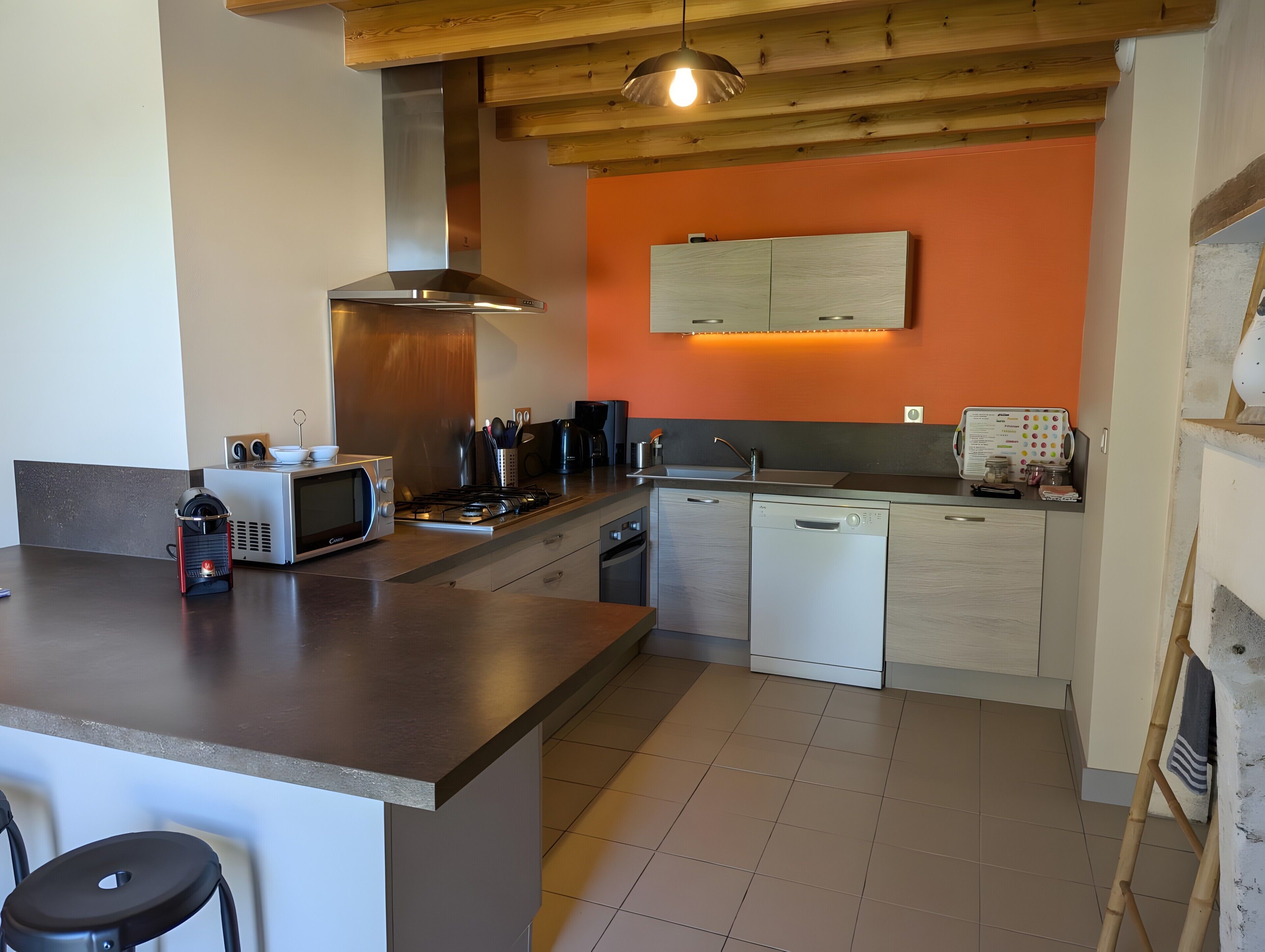 A modern kitchen with a central island, built-in appliances, and a wooden ceiling.