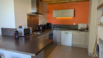 A modern kitchen with a central island, built-in appliances, and a wooden ceiling.