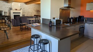 A modern kitchen with a central island, bar stools, a microwave, and a stove. - Holiday Home 'La Bonne Chauffe - Serpentin' with Shared Pool, Private Terrace and Wi-Fi (Verrières)
