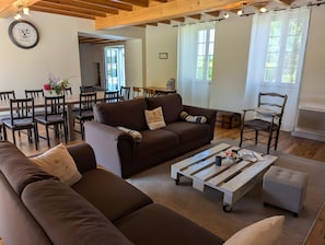 Una sala de estar con sofás marrones, una mesa de centro de madera y un comedor con una mesa y sillas.