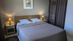 A neatly made bed with a headboard, two bedside lamps, a framed artwork on the wall, and a window with curtains. - Holiday Home 'La Bonne Chauffe-Col De Cygne' with Shared Pool, Private Terrace and Wi-Fi (Verrières)