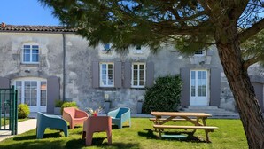 A stone building with a patio area featuring outdoor furniture and a picnic table. - Holiday Home 'La Bonne Chauffe-Col De Cygne' with Shared Pool, Private Terrace and Wi-Fi (Verrières)