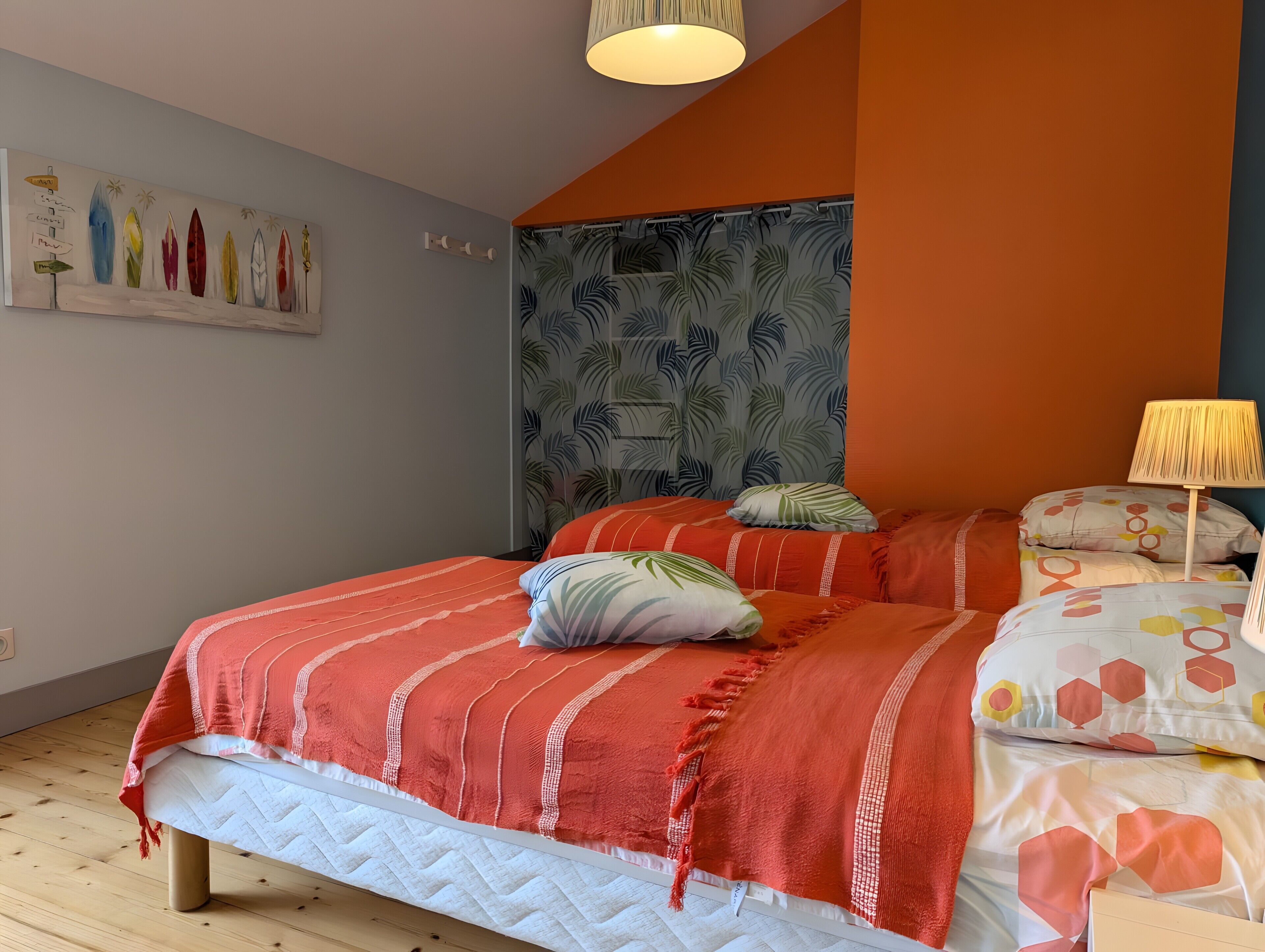 Een slaapkamer met een bed, kussens, een muurschildering en een kamerbreed gordijn.