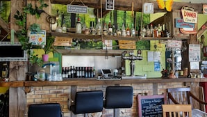 A bar area with wooden shelves, bar stools, and various bottles.