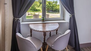 A room with a window, a small table, two chairs, and a view of greenery outside.