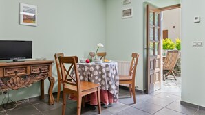 Een eethoek met een tafel, stoelen, een televisie en uitzicht op het omliggende landschap.