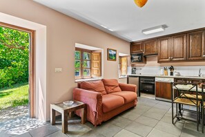 Eine moderne Küche mit Holzschränken, ein Essbereich mit Tisch und Stühlen sowie eine Sitzecke mit einer Couch.